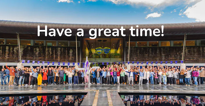 Large group of Holiday Extras staff outside a modern building with the message Have a great time above them